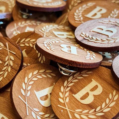 Wooden buttons with engraved 'B' and leaf design on a dark surface